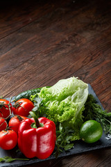 Artistic still life of assorted fresh vegetables and herbs on rustic wooden background, top view, selective focus.