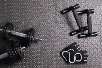 Obraz na płótnie Canvas Accessories for fitness at home, mat, dumbbells of varying weights, gloves for sports. the concept of sport, fitness and a healthy lifestyle. 