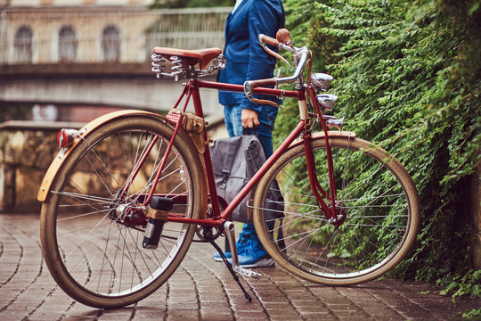 Male dressed in casual clothes, standing near a retro bicycle in a park.