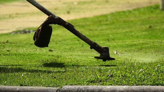 Lawn mowing.
Professional gardener mowing lawn at central park property with gasoline trimmer,HD slow motion.