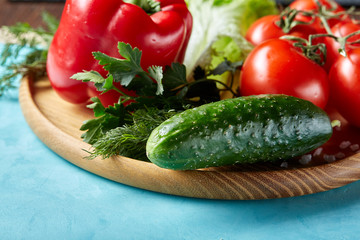 Refreshing close-up still life of assorted fresh vegetables and herbs on blue background, top view, selective focus.