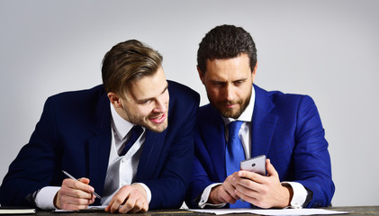 Managers with happy faces discuss project and surf internet.