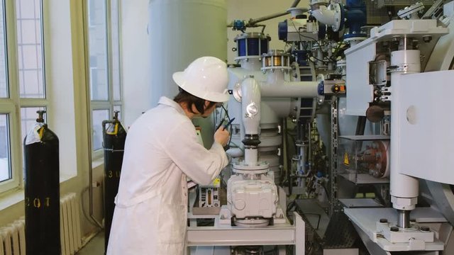 An engineer in a white helmet and goggles examines the gas installation on a production basis.