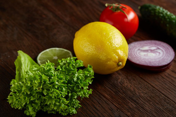 Healthy breakfast with tomatoes, letucce, lime on wooden background, close-up, selective focus, top view.