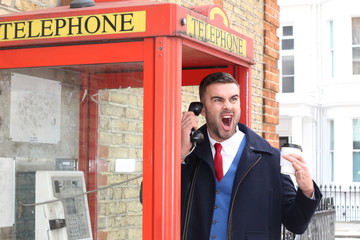 Angry businessman calling by payphone 