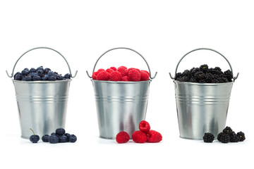 Summer berries Blueberry, Raspberry, Blackberry in small buckets on white isolated background.