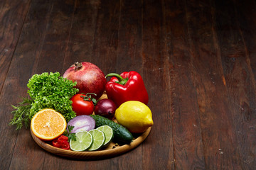 Still life of fresh organic vegetables on wooden plate over wooden background, selective focus, close-up