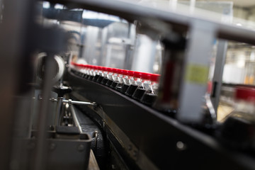 Bottling factory - Black juice or soft drink bottling line for processing and bottling juice into bottles. Selective focus.