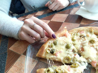 Pizza with olives in hand on a table in a cafe