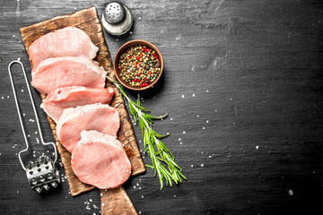 Raw pork steaks with spices and herbs.