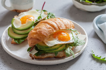 Breakfast with Croissant sandwiches with Fried Egg, Salad Leaves and avocado