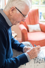 Fototapeta na wymiar Senior Man Doing Crossword Puzzle At Home