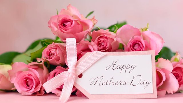 Woman placing pink roses on pink wood table, Mother's Day background closeup.
