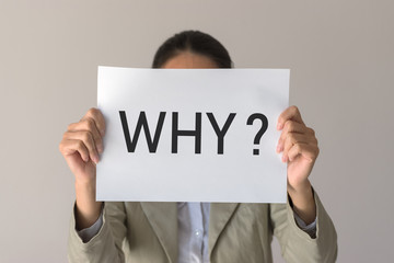 A woman holds a banner with the inscription WHY?