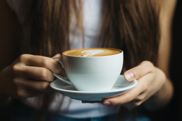 woman relaxing near the window with coffee in hands in a vintage restaurant