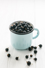 Fototapeta na wymiar Black currant in tea cup on a white wooden table