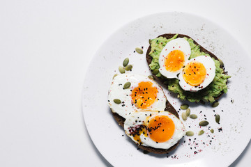 sandwich with fresh vegetables, avocado, hard-boiled eggs and pumpkin seeds with olive oil and bread. healthy diet or vegetarian food on a white background. salad with yolks on toast. top view
