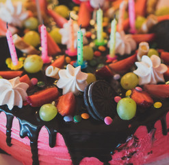 Pink chocolate cake with strawberries, meringues and grapes.