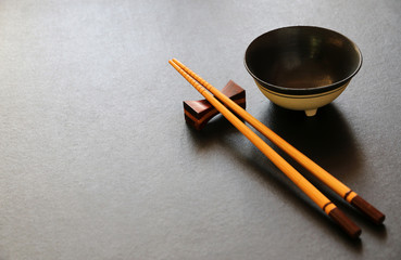 wood chopsticks and ceramic bowl on black table background