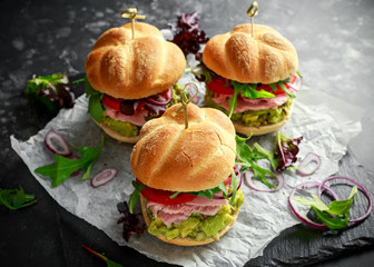 Fresh home sandwich with avocado guacamole, tomatoes, arugula, red onion and ham.