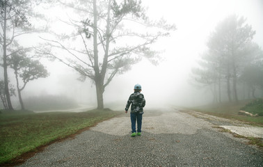 Little boy walking through the mist in forest : Thailand