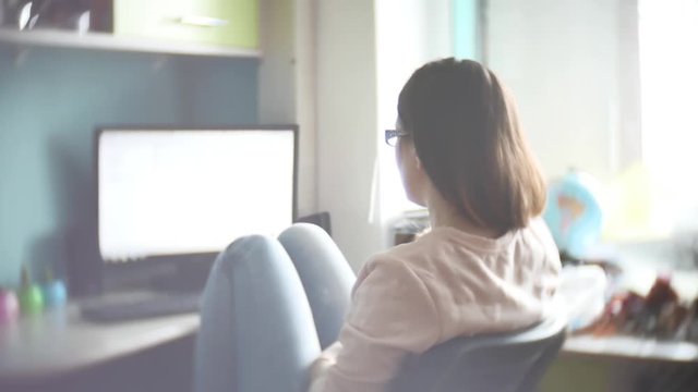 girl in jeans and sweater designer online while sitting at desk in modern office slow motion video, works on the computer search on the Internet. Female freelancer working from home on computer