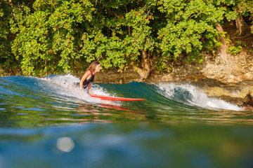 female surfer riding wave on surfboard in ocean
