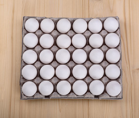 White chicken eggs in a cardboard package, wooden background