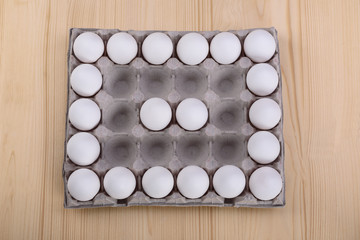 White chicken eggs in a cardboard box with empty spaces, backgro