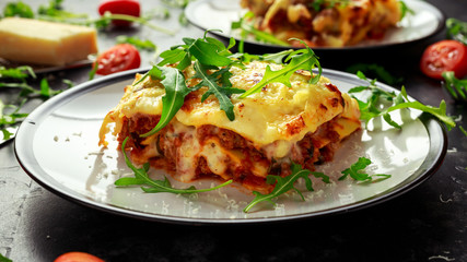 Homemade lasagna with minced beef bolognese and bechamel sauce topped wild arugula, parmesan cheese - obrazy, fototapety, plakaty