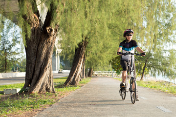 Joyful senior Asian woman riding a bicycle in park
