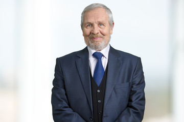 Old boss in suit portrait. Bright blurred background.