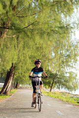 Joyful senior Asian woman riding a bicycle in park