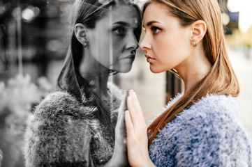 Self reflection portrait of amazing young girl in mirrored window. Unusual strange pretty woman person with sensual face looking at herself in showcase. Alter ego. Female state of mind. Other myself.
