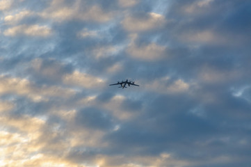 Silhouette of the plane in the clouds at sunset