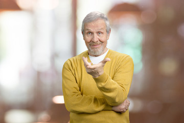 Old man asking a question what is it. Portrait of arrogant grandfather is criticizing. Abstract blurred background.