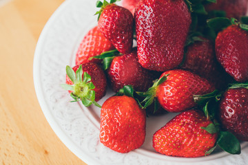 ripe strawberries in a white plate on a wooden table. Delicious red healthy natural berry.