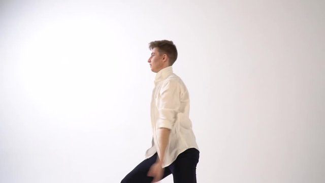 Man in white shirt dancing ballet pas on white background