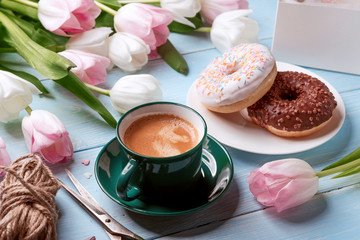 Obraz na płótnie Canvas donuts, coffee and tulips on a blue wooden background.