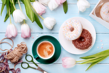 Fototapeta na wymiar donuts, coffee and tulips on a blue wooden background.