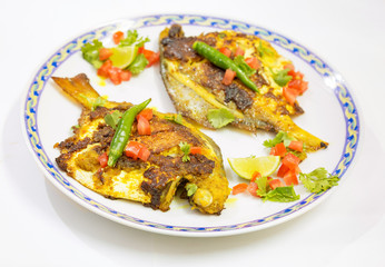Crispy spicy fried Pomfret fish garnished with vegetables. A popular Indian fish cuisine.