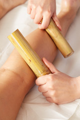 Woman having bamboo stick massage at day spa