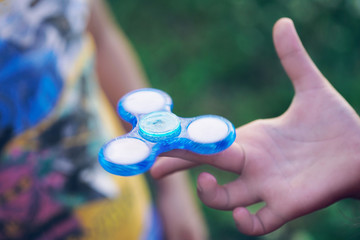 Young boy play with fidget spinner stress relieving toy. Just hands with toy.