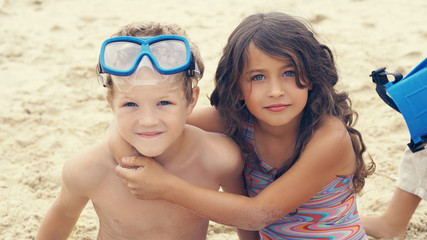 Portrait of children on the beach in summer. Little girl hugs her brother.