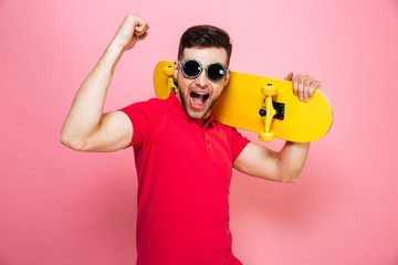 Portrait of a joyful young man in sunglasses celebrating