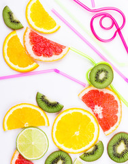 Citrus slices and colored straws on white background