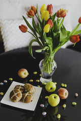 Easter hot cross buns and chocolate eggs with apples and flowers