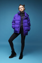 Young fashion woman in short violet down jacket and leather boots