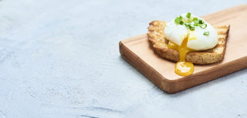 Tasty poached egg on toast over rustic background