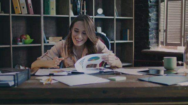 Happy business woman smiling and analyzing data in office. Female boss looking data graphics in home office. Casual businesswoman reading report document. Female employee working with smile in office